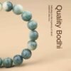 Green bodhi beaded bracelet shown in side curve with carved beads and central metal charm