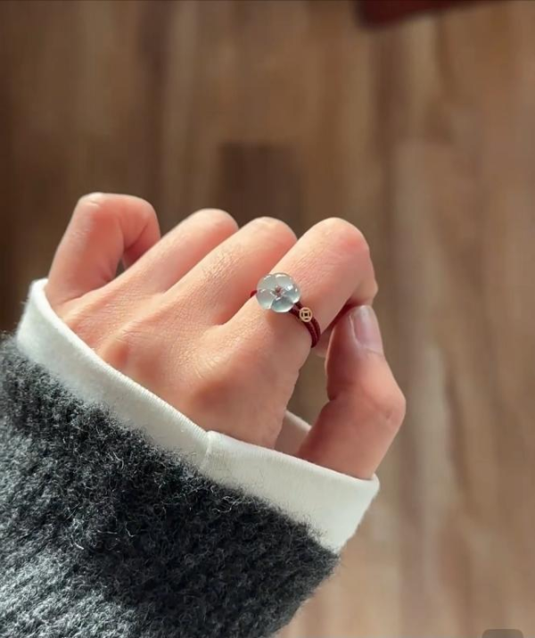 Natural jadeite ring with round light jade stone on red cord band in hand