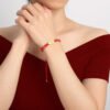 111 angel number red string bracelet worn on the wrist, hands clasped, with a dark red off-shoulder top