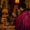 Fragrance ritual setup with a small perfume bottle on a table beside a praying person