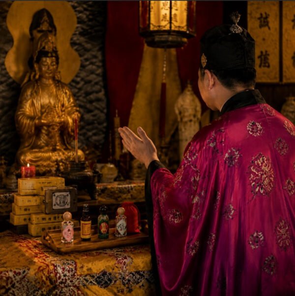 Fragrance ritual setup with a small perfume bottle on a table beside a praying person
