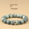 Green bodhi beaded bracelet with carved beads and central metal mantra charm, flat lay