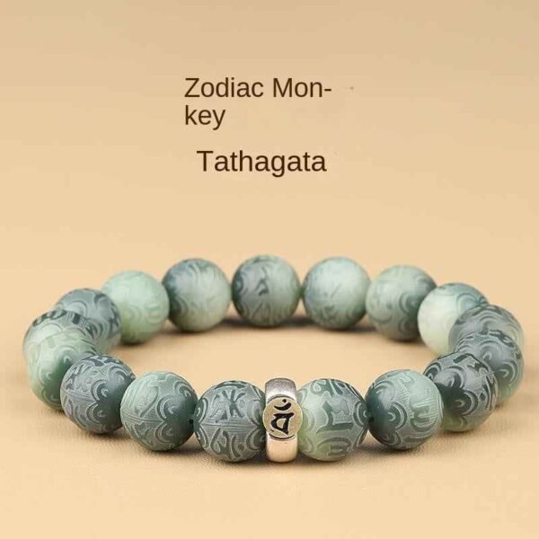 Green bodhi beaded bracelet with carved beads and central metal mantra charm, flat lay