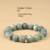 Green bodhi beaded bracelet with carved beads and central metal charm on light background