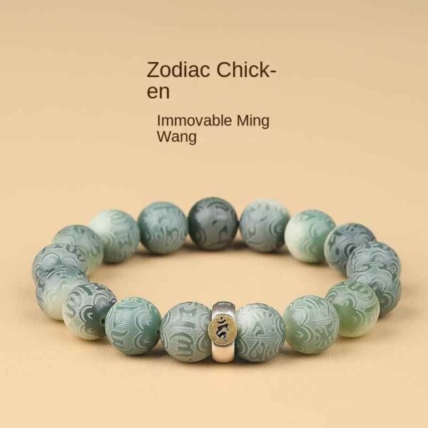 Green bodhi beaded bracelet with carved beads and central metal charm on light background