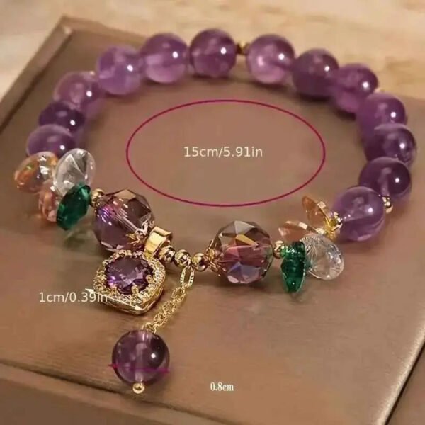Amethyst gemstone bracelet with purple bead strand, gold accents, green stones, and hanging purple charm.