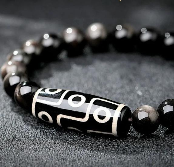 Black obsidian bead bracelet with white-patterned silver tube centerpiece, close-up